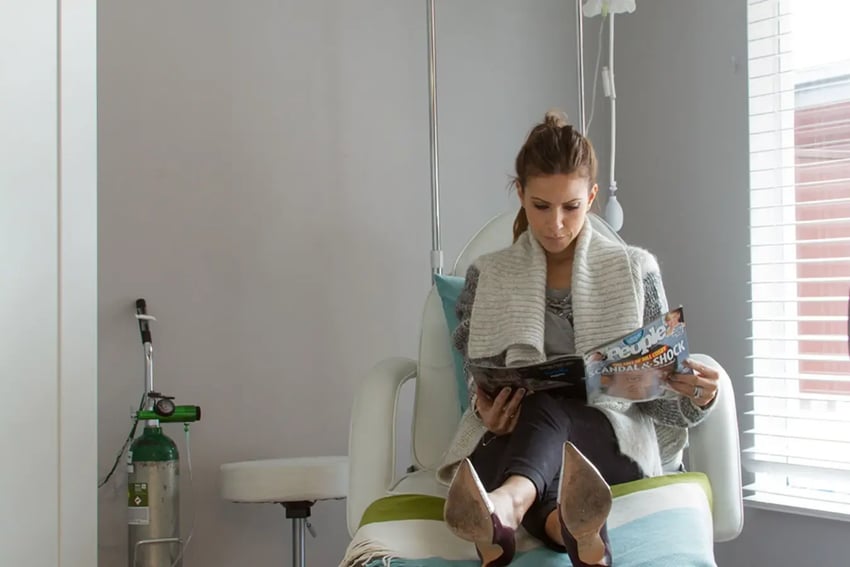 Hydration Room Patient Reading Magazine While Receiving IV Therapy
