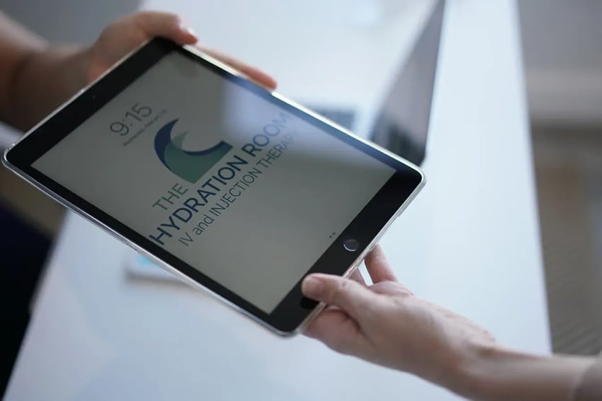 Hydration Room Wellness Coordinator Handing Ipad to Patient