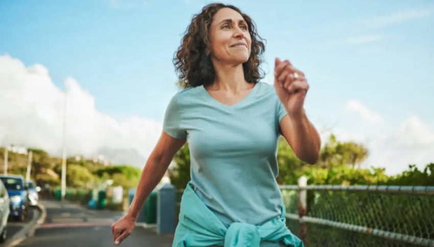 Smiling mature woman out for a power walk in summer