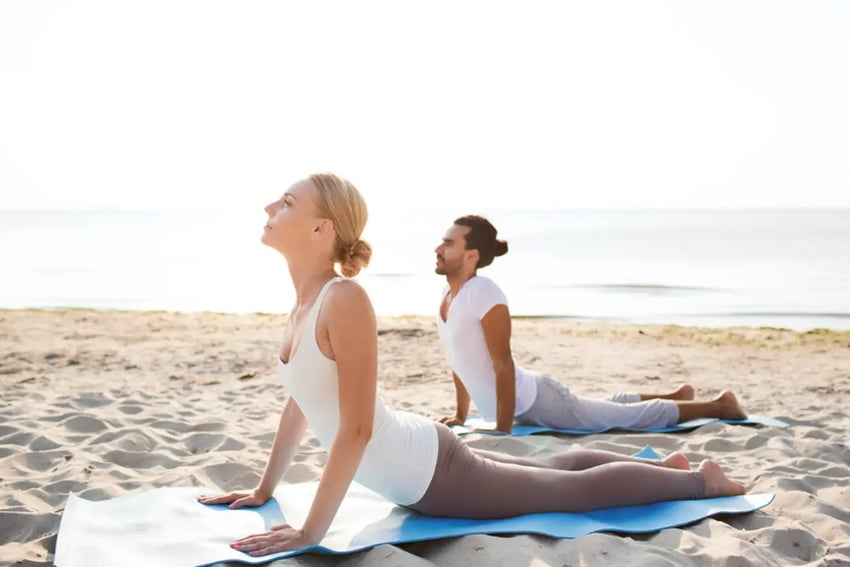 Two people doing yoga on the beach