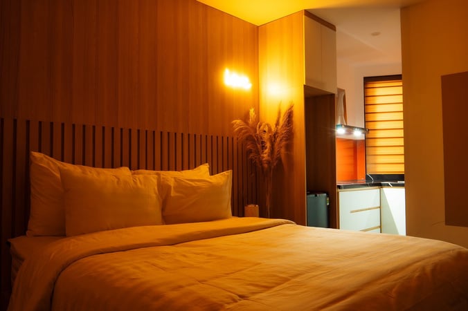 An inviting bedroom with wood-paneled walls, soft lighting, and cozy bedding