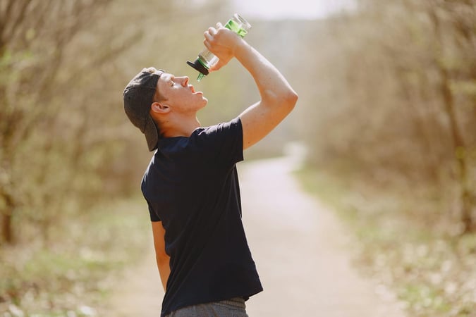 A young man in sportswear hydrates with a water bottle