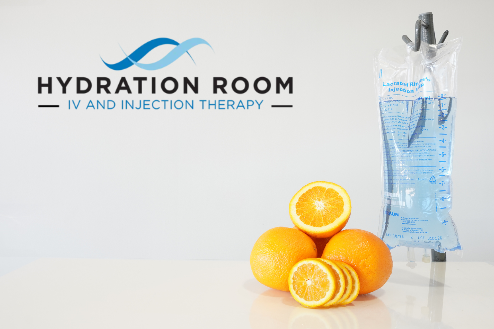 Hydration Room logo on a light gray background, with a hanging IV fluid bag and fresh oranges arranged at the bottom
