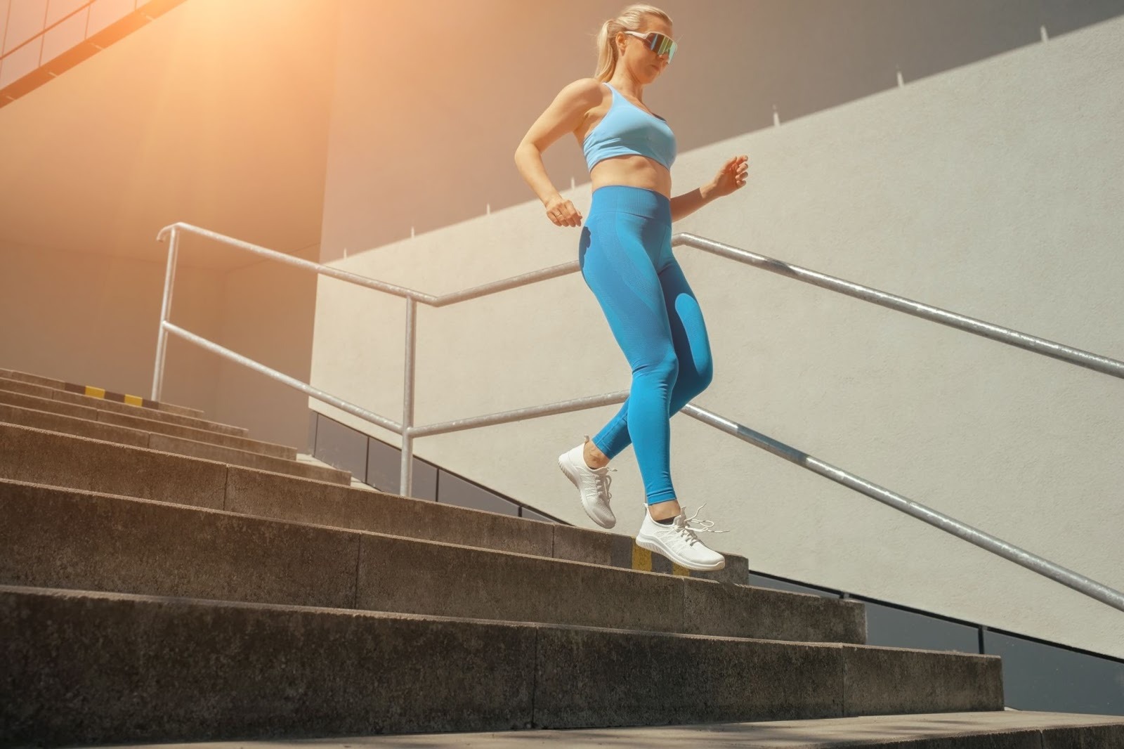 A middle-aged woman in blue leggings runs down a flight of stairs.