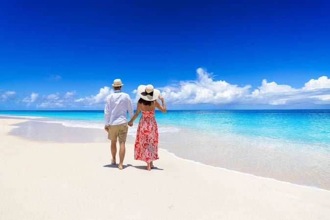 A happy couple strolls on a beach on a beautiful day with vibrant blue skies