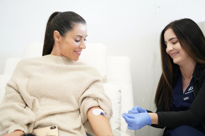 A medical professional from the Hydration Room giving a woman an NAD+ energy shot 