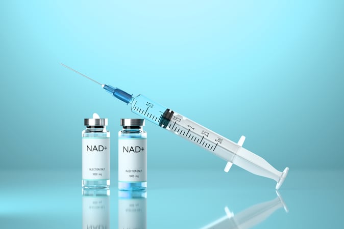 Medical syringe with a needle and vials with NAD+ solution on a blue background