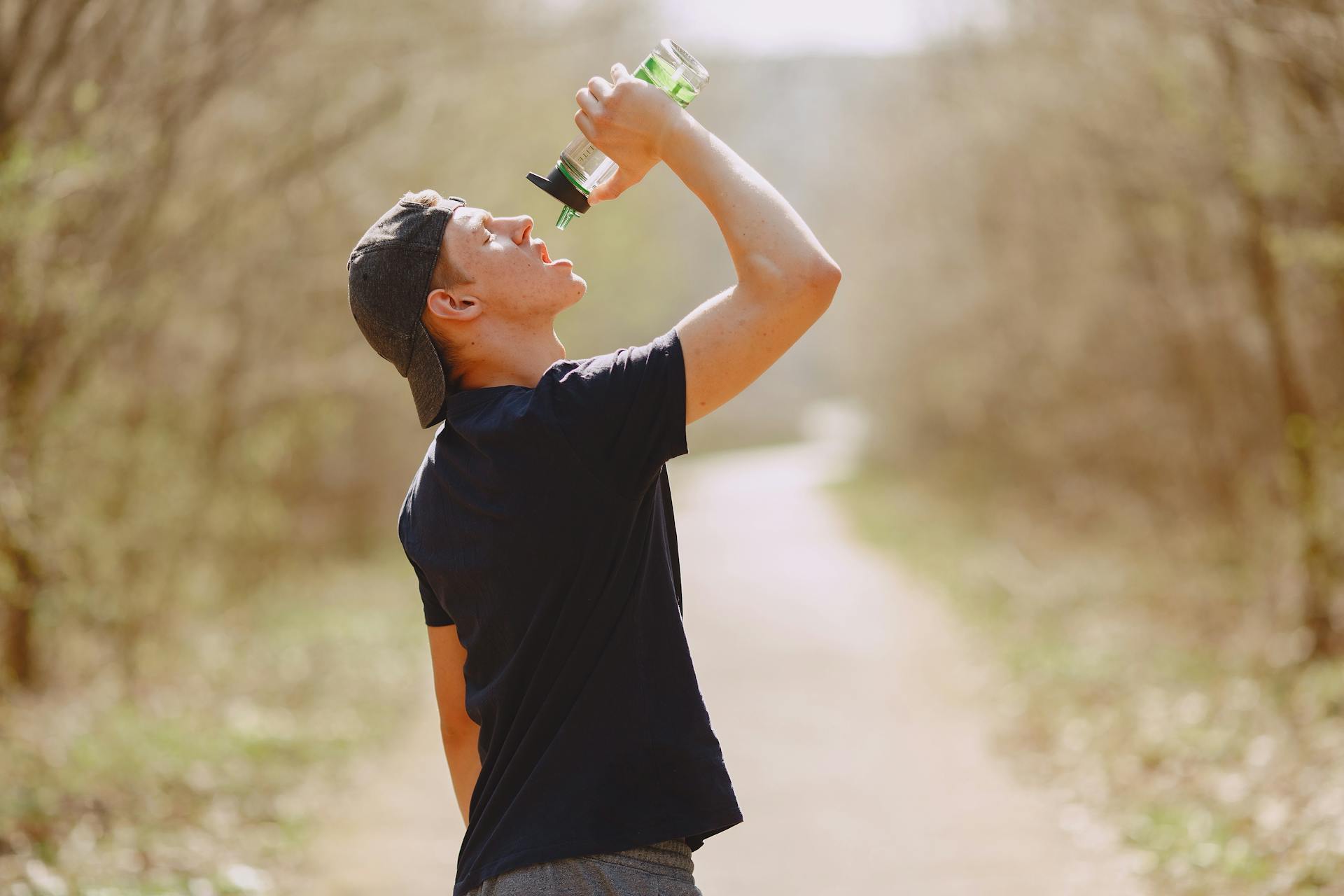 A young man in sportswear hydrates with a water bottle