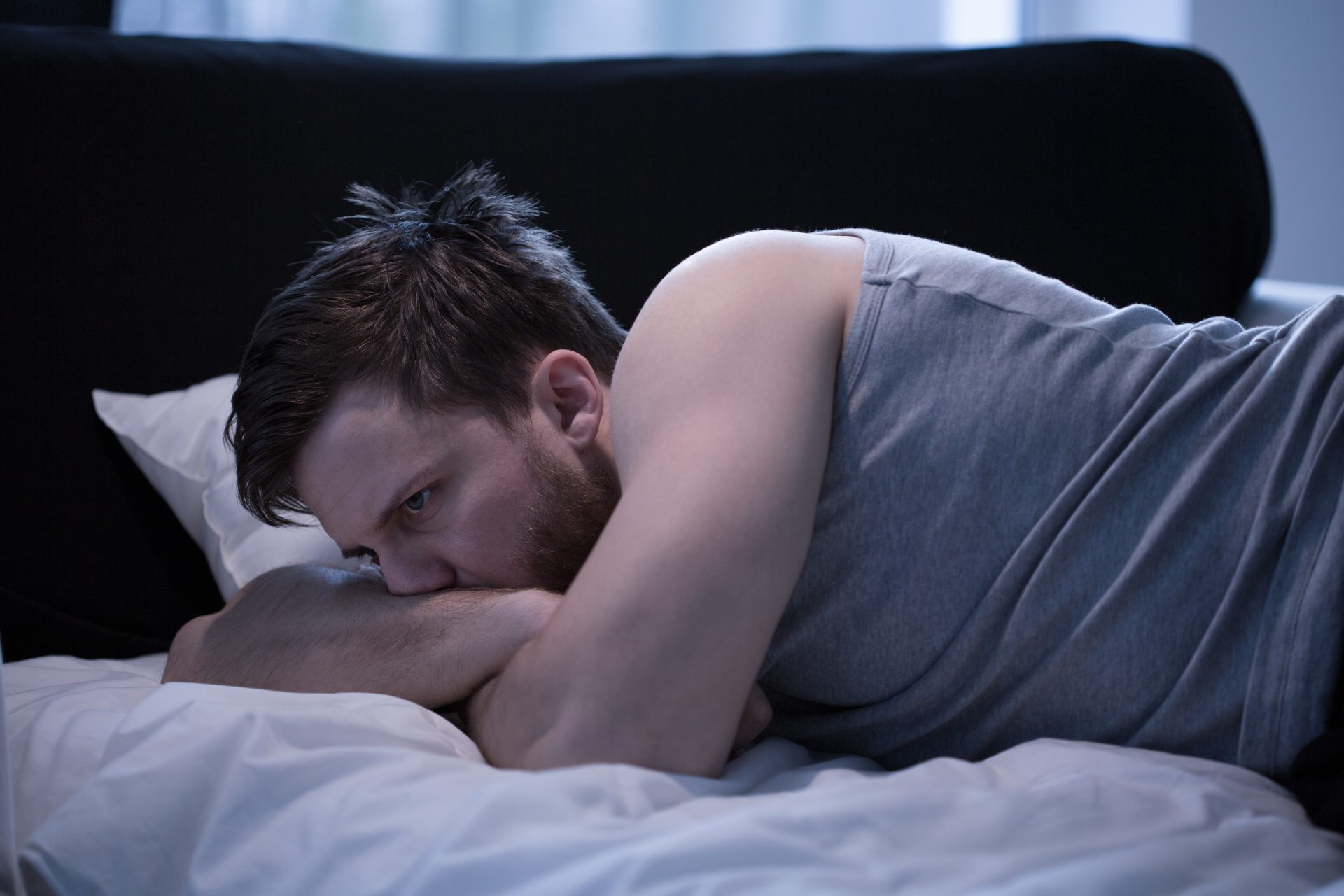 A jet-lagged man lying sleepless in bed at night
