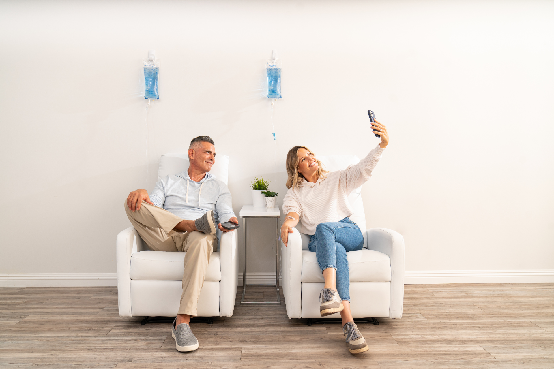 Man and a woman receiving IV therapy at Hydration Room while the woman takes a selfie 